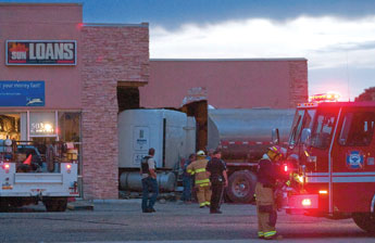 A Gallup Fire Department firefighter examines wreckage beneath a fuel tanker lodged into Sun Loans on U.S. 491 Friday in Gallup. © 2011 Gallup Independent / Adron Gardner 